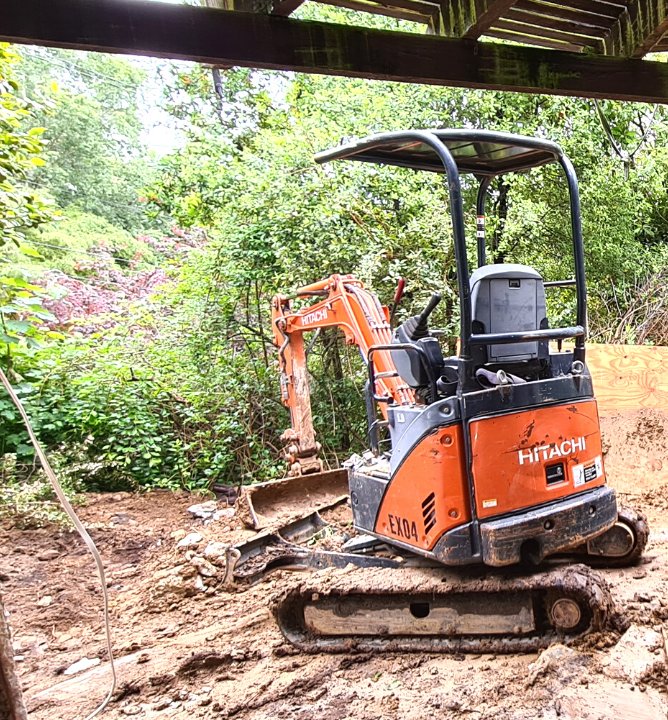 Orange digger removing clay and soil from a building site.